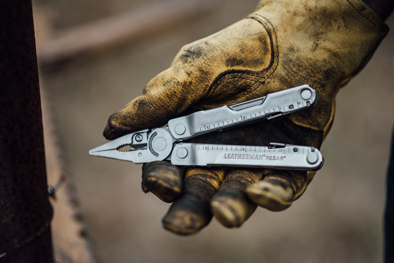 Coyote tan 17-in-1 multi-tool held in gloved hand, tools extended