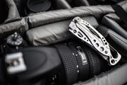 Leatherman Skeletool multi-tool resting beside a camera lens in a bag