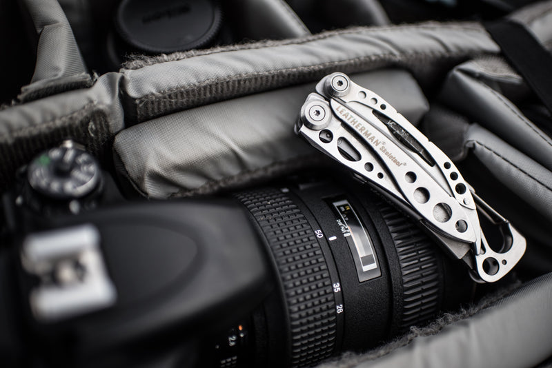 Leatherman Skeletool multi-tool resting beside a camera lens in a bag