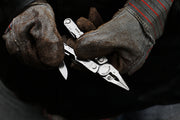Stainless steel 17-in-1 multi-tool held in gloved hand, blades extended