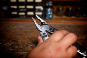 Stainless steel multi-tool held in hand, blades and pliers extended