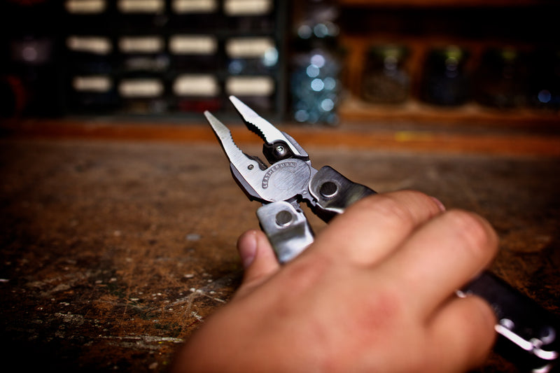 Stainless steel multi-tool held in hand, blades and pliers extended
