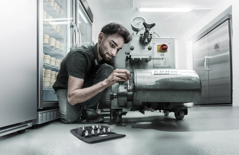 Mechanic using the mini ratchet tool near a workshop machine